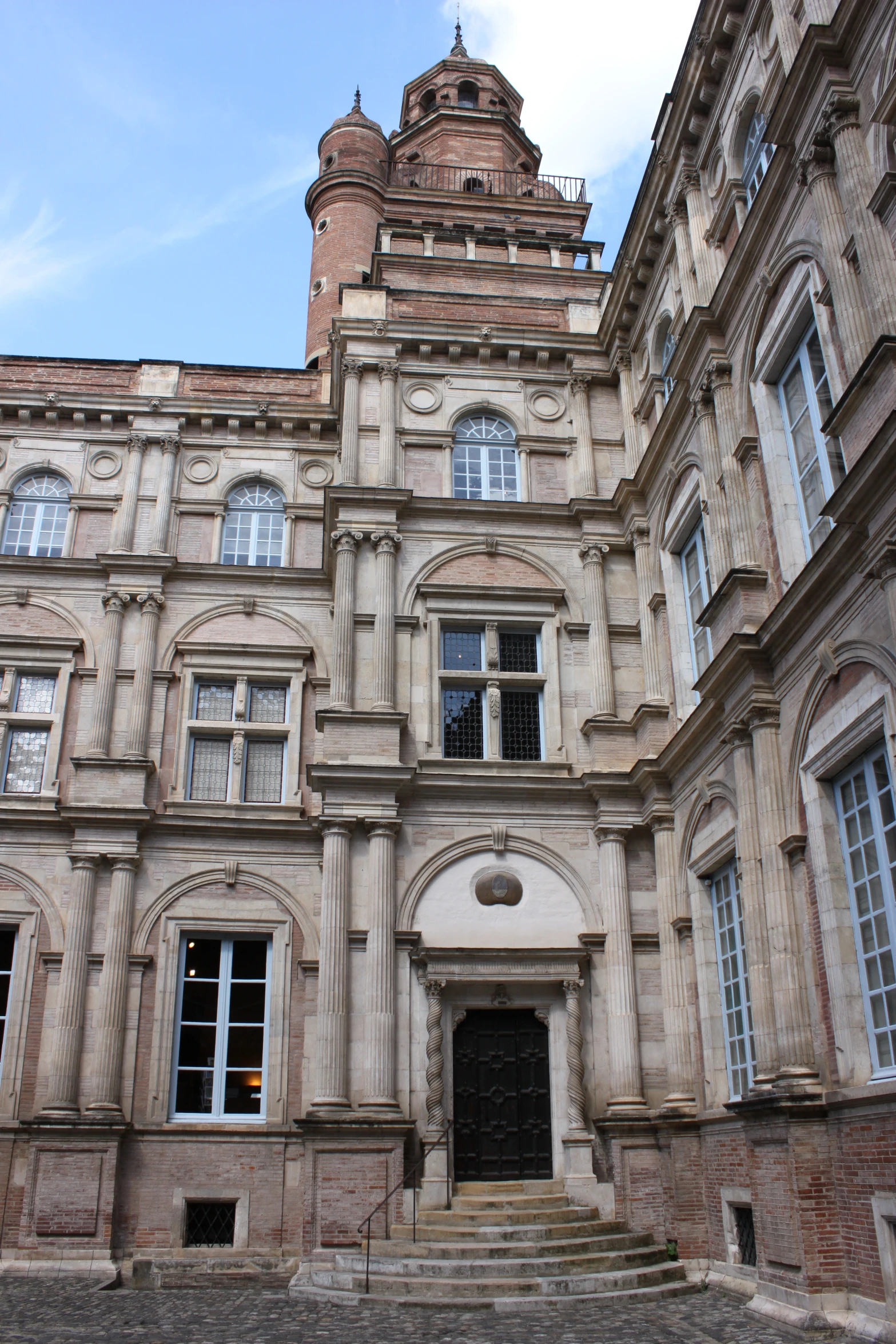 a tall, tan building with windows and some arches