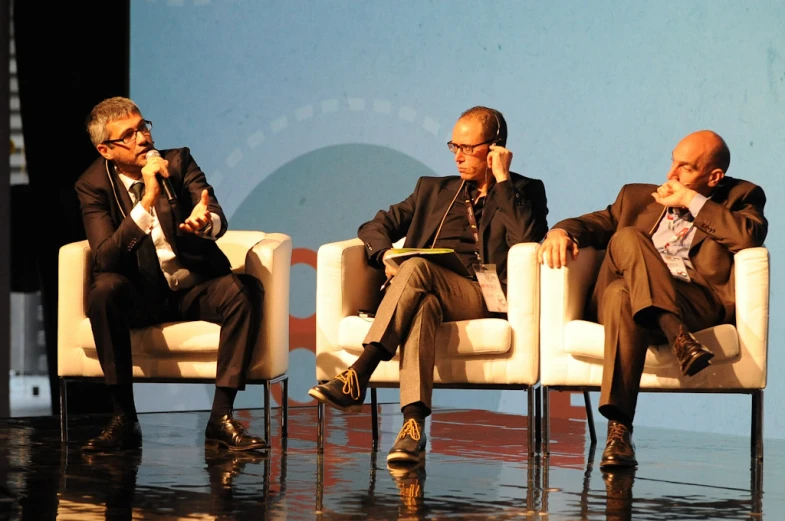 two men in suits and one with glasses on a stage