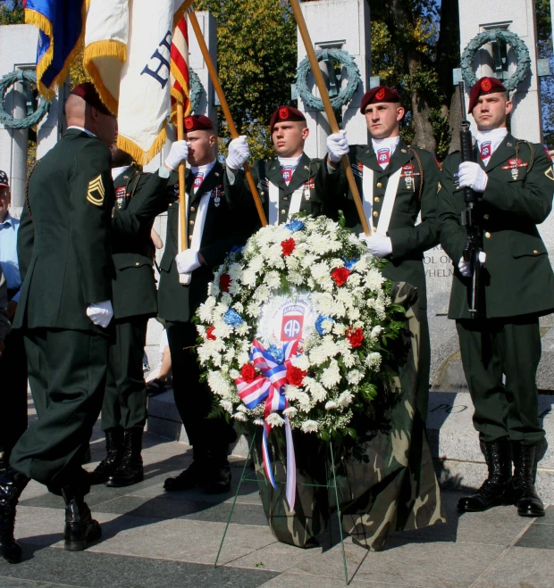 men in uniform with wreath and flags