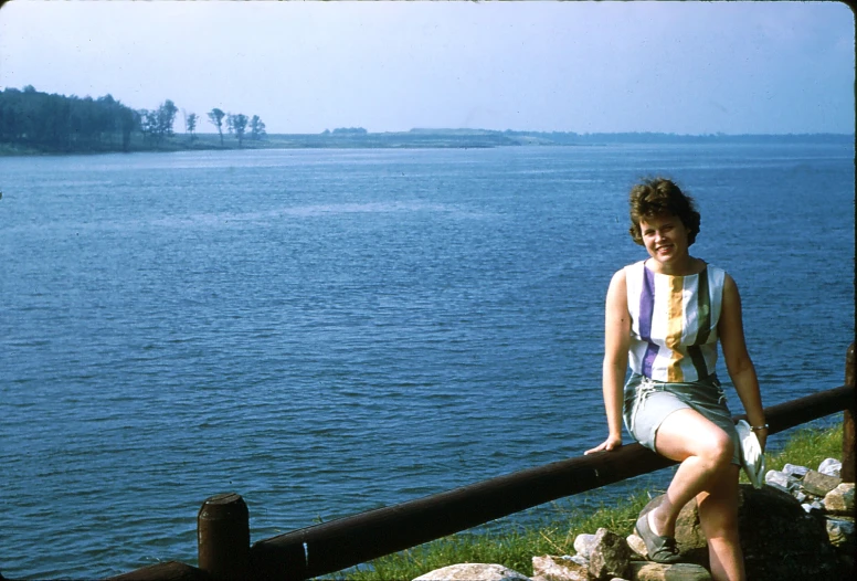 a girl leaning against a railing on a sunny day