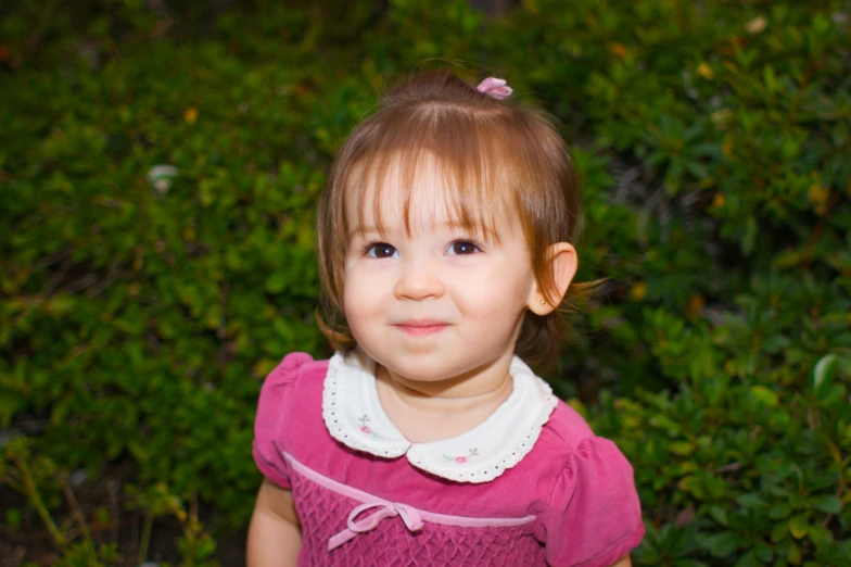 a cute little girl standing in a garden