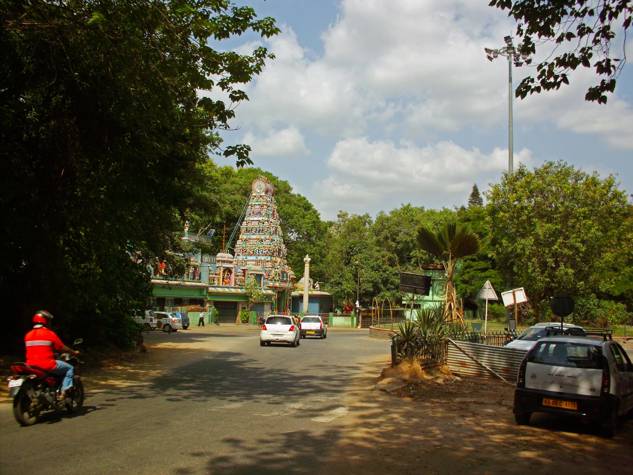 traffic driving on the road past an indian temple