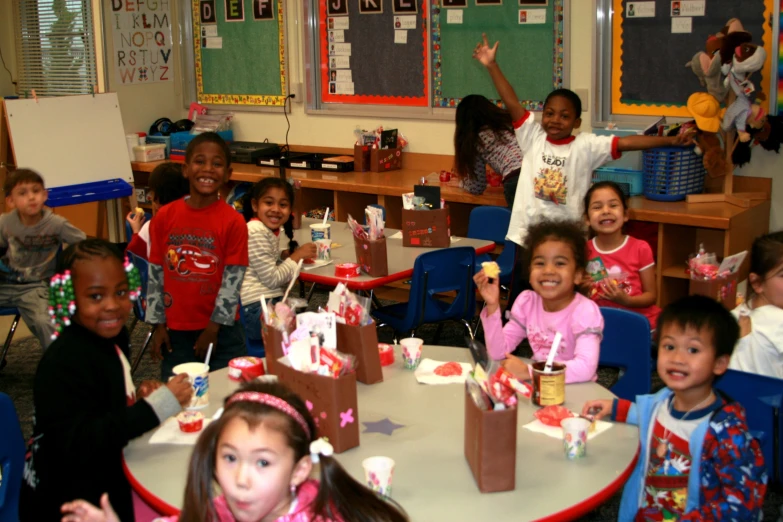 a group of children sit around a table eating cake