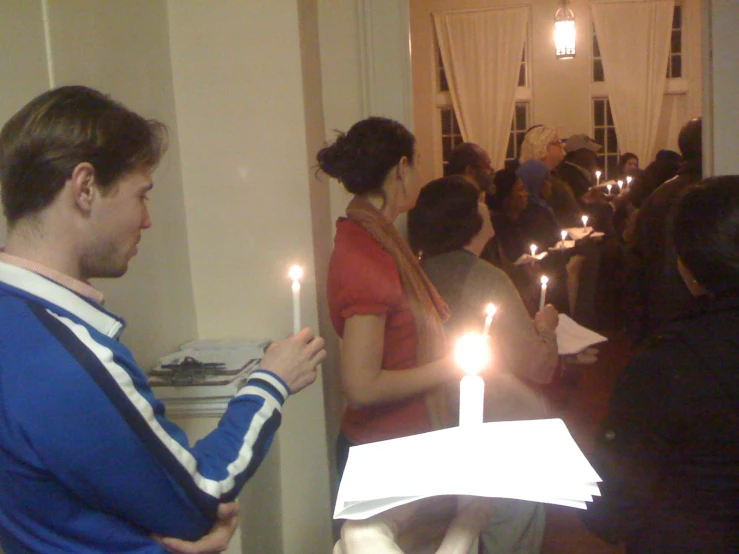 people in a room are lighting candles on a small cake