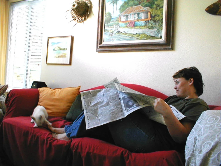 a woman is reading a newspaper on the couch