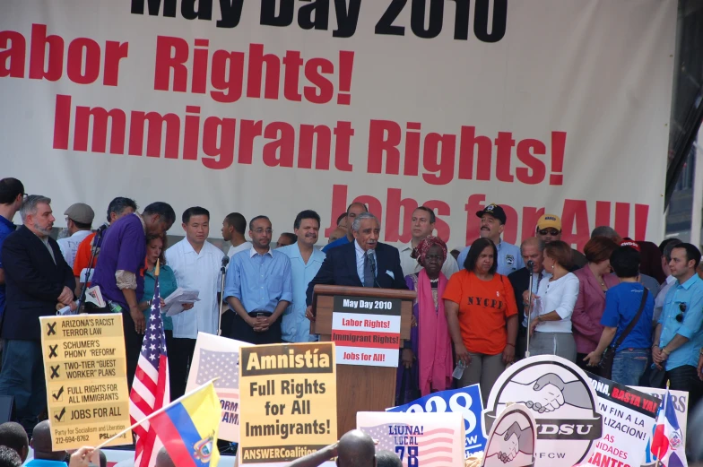 a man in a tie standing behind a microphone in front of several signs