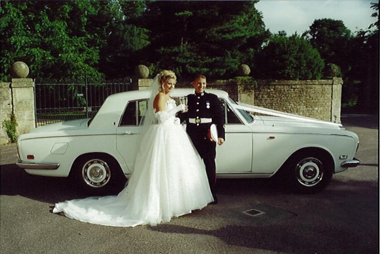 a man and woman posing in front of a car