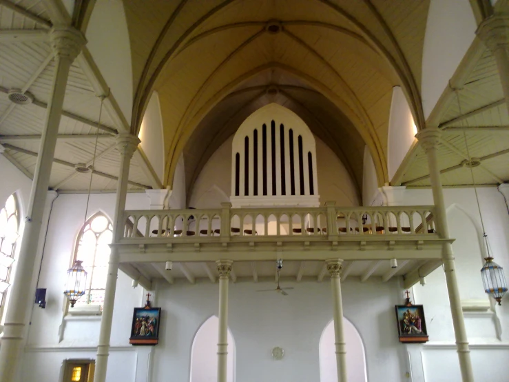 the ceiling in a large building has a pipe organ and pillars