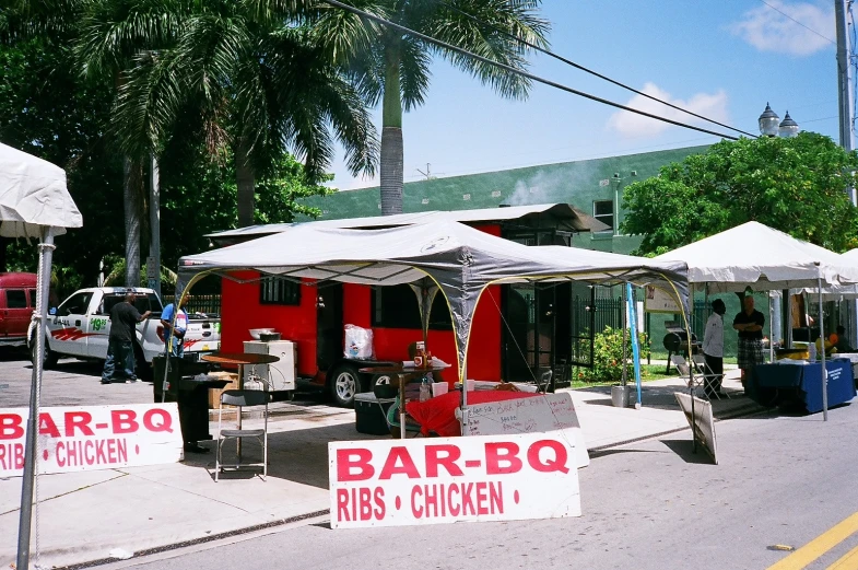 several outdoor stands and food carts with signs on the ground