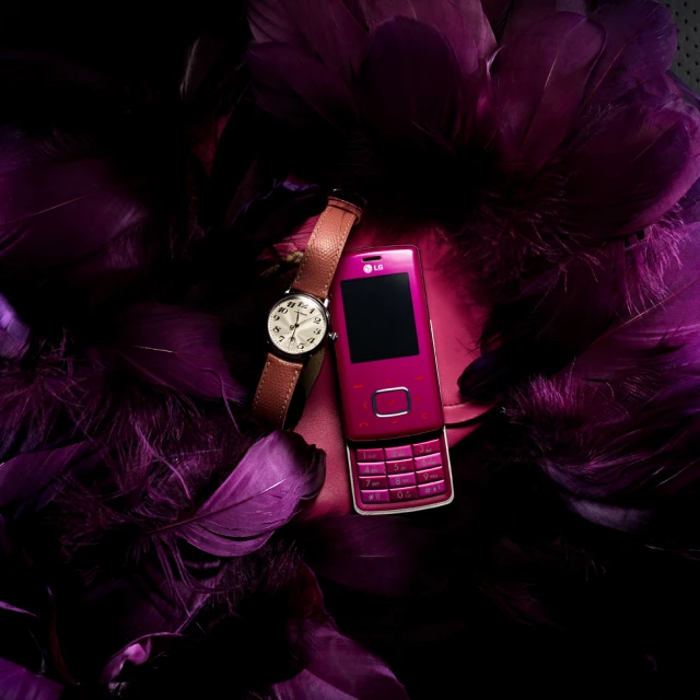 a pink cell phone next to purple feathers