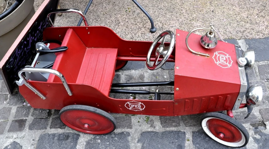 there is a red pedal wagon that looks like an old car