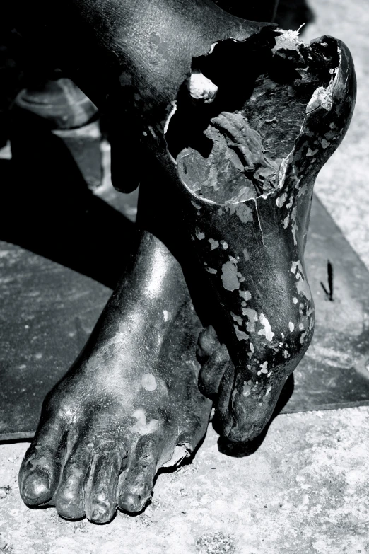 the black and white image shows an upside down view of a person with dirty shoes