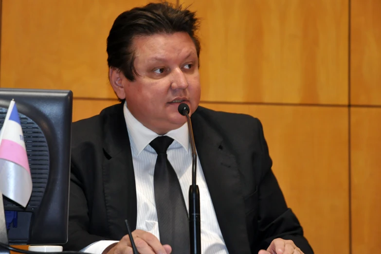 a man is sitting at a desk and talking into a microphone