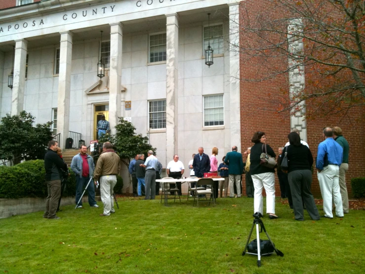 people gather in front of a brick building