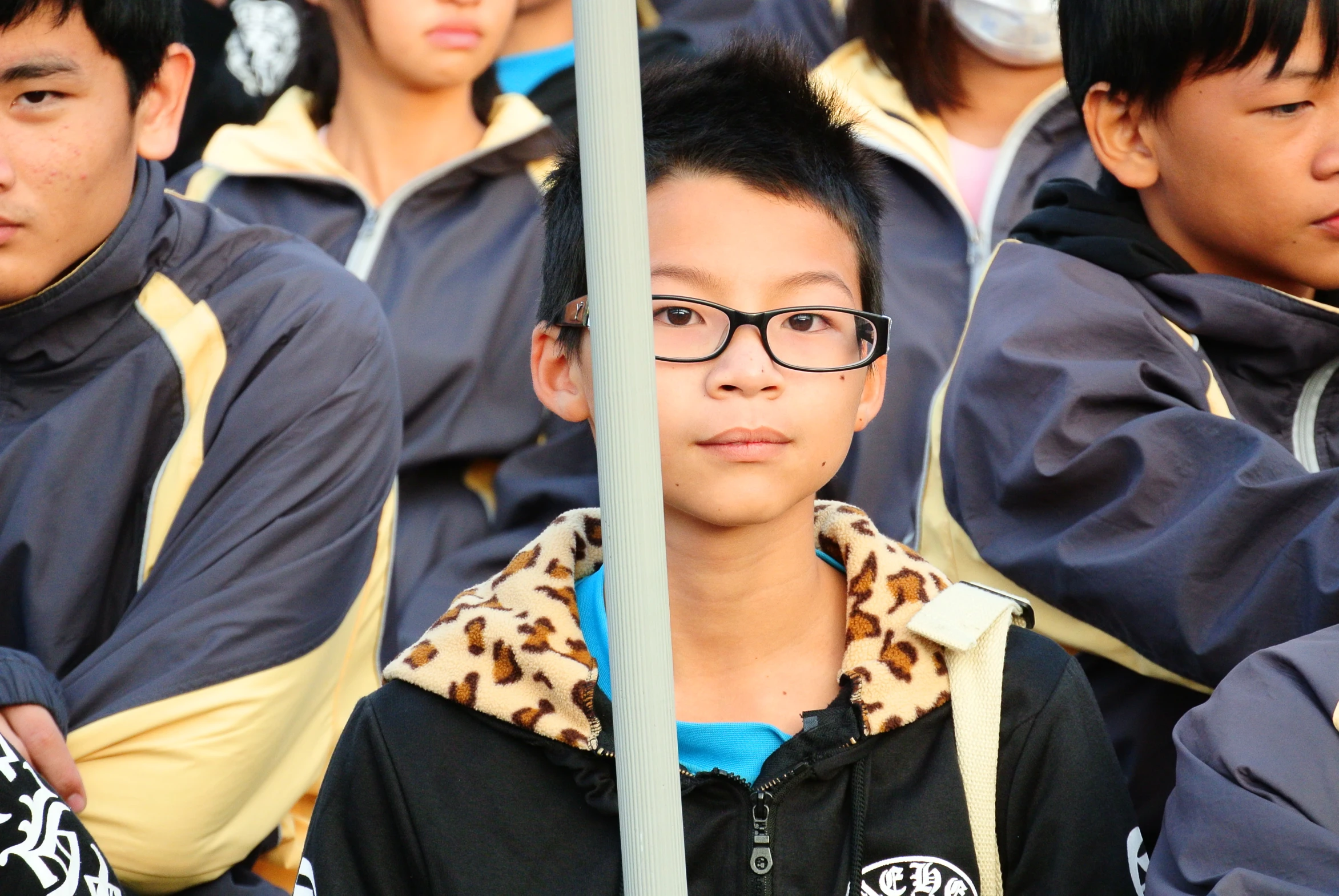 children with eyeglasses on their faces stand by an pole