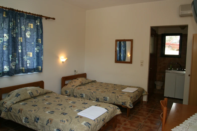 two beds are pictured in this bedroom with a window