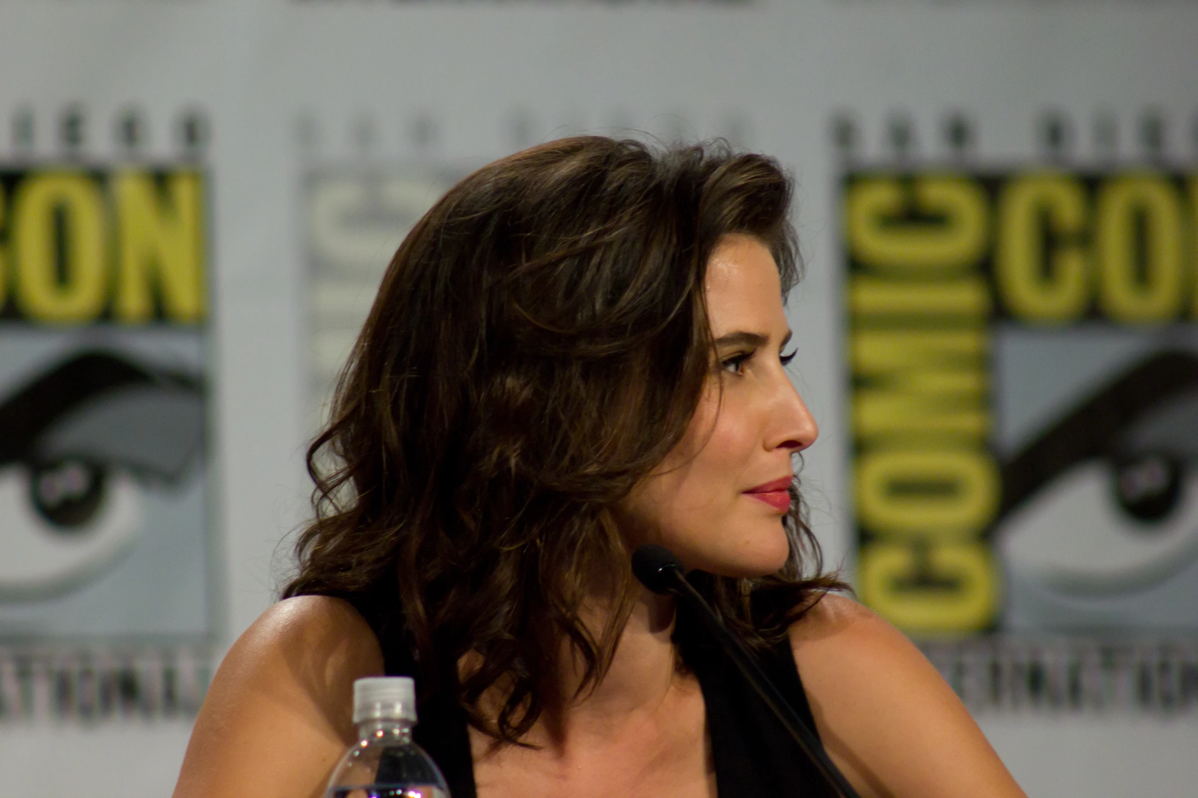 a beautiful woman sitting down next to a bottle of water