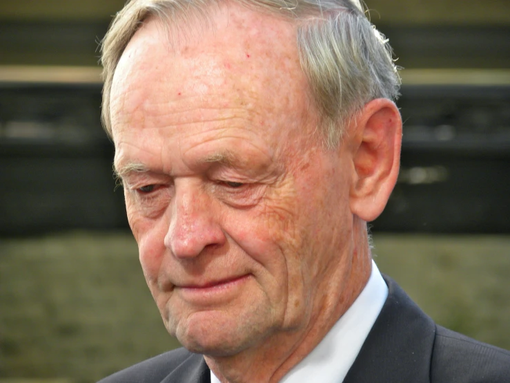 an older man in a black suit and red tie