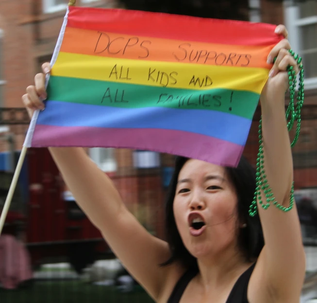 a woman is holding up a rainbow sign