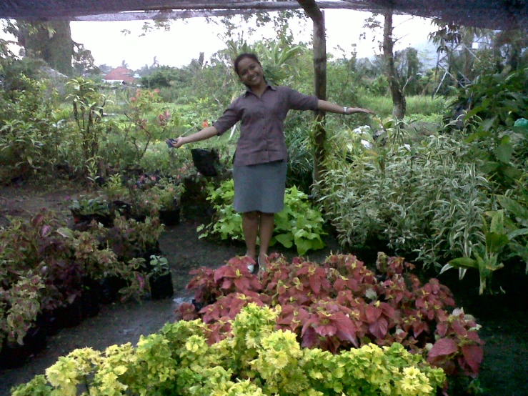 a woman posing in a garden area with lots of flowers