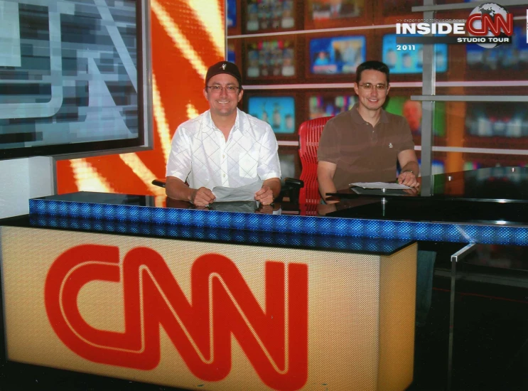 a tv studio with two men sitting in chairs