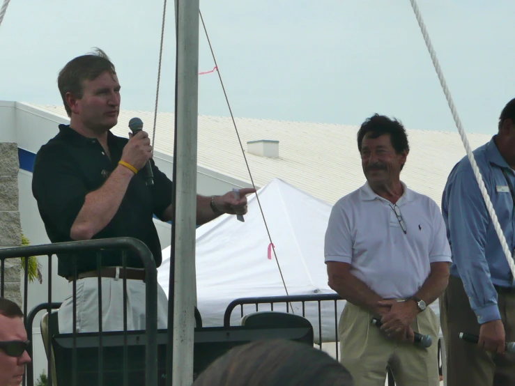 three men stand on top of a white tent