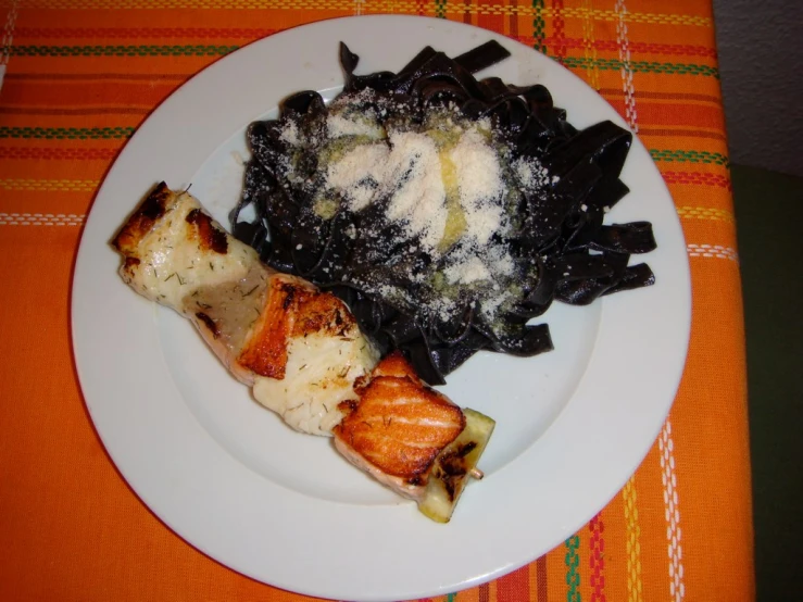 some salmon are placed on top of pasta on a white plate