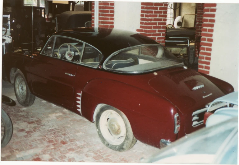 a red old sports car parked in a garage