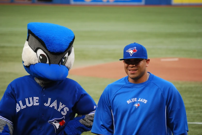 two toronto blue jay's mascot men with baseball uniforms on at a stadium