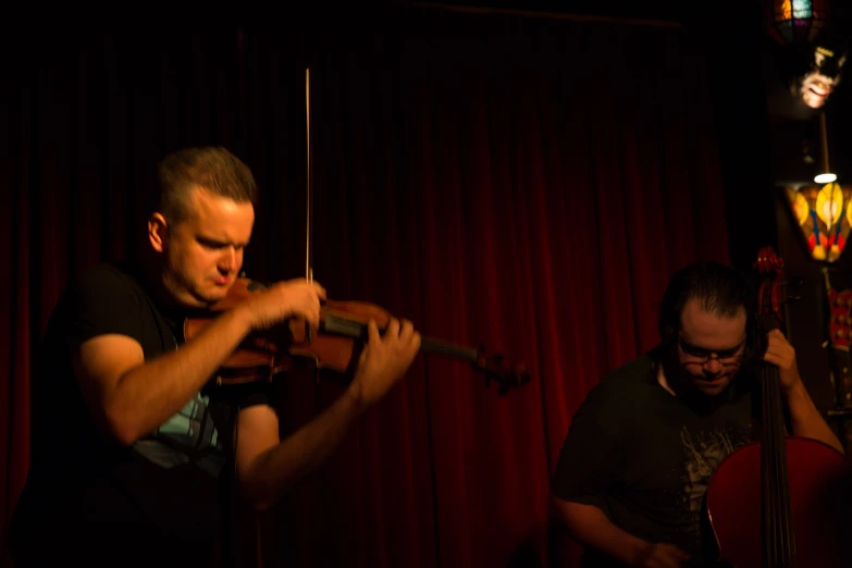 a man playing violin while another man watches