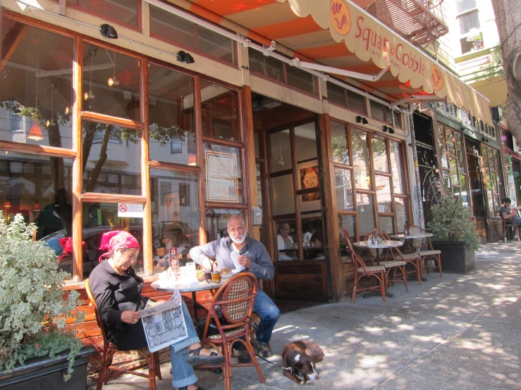 two people sitting outside of a store with their dogs