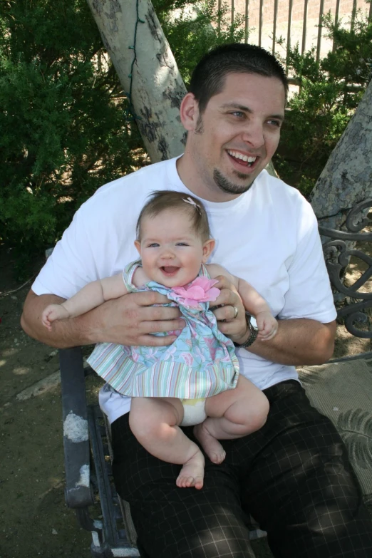 a man is sitting on a bench holding a baby