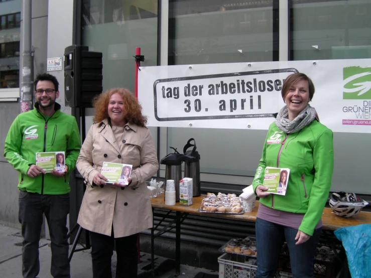 three people standing next to a table with food on it