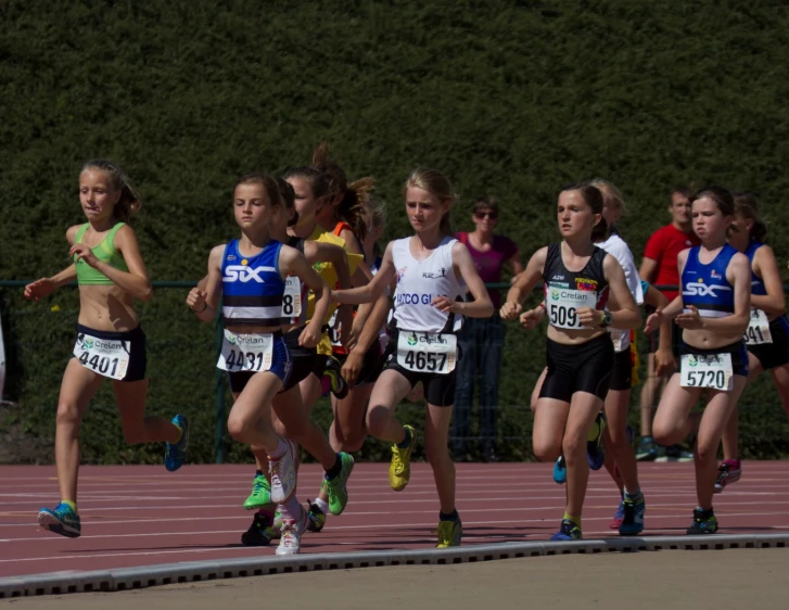 girls running in competition on track with trees