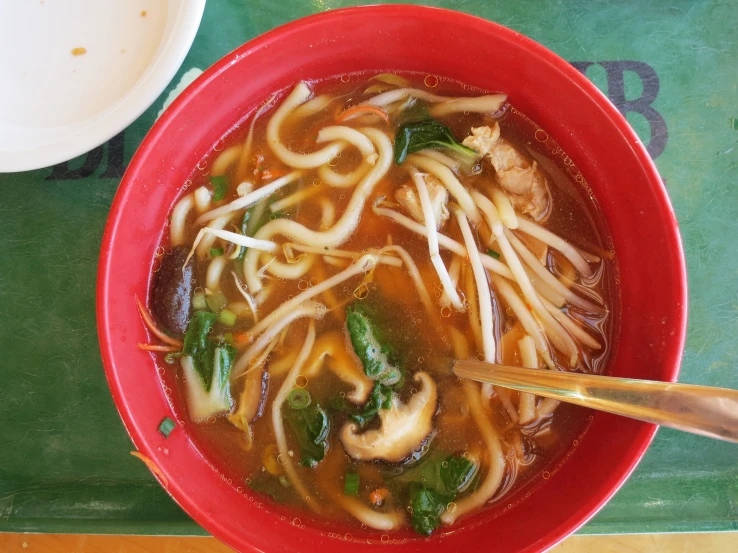 a red bowl of asian noodle soup on top of a green counter