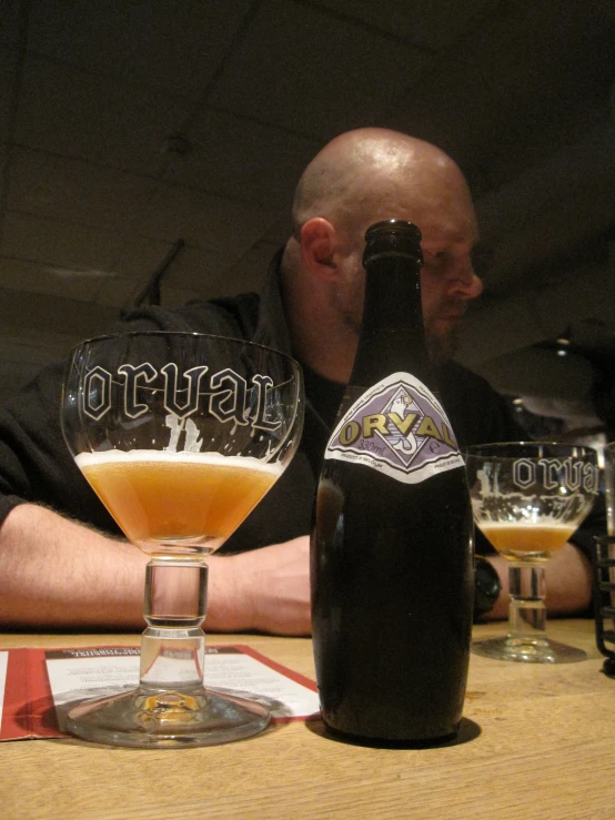 an older man sitting with a beer and a bottle