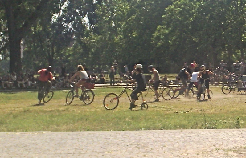 a group of bicyclists ride in front of a crowd of people