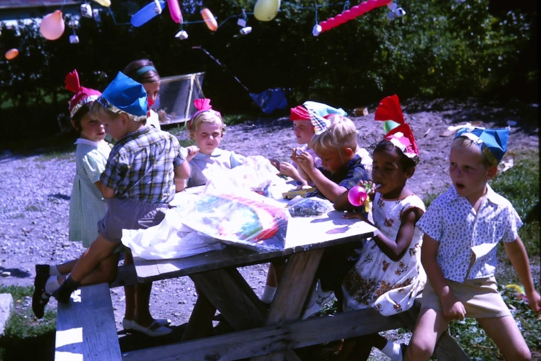 some s at a picnic table with a large sheet of cake