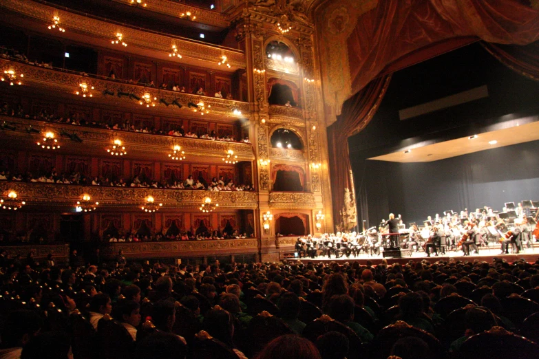 an auditorium filled with people standing on the stage with lights in their hands