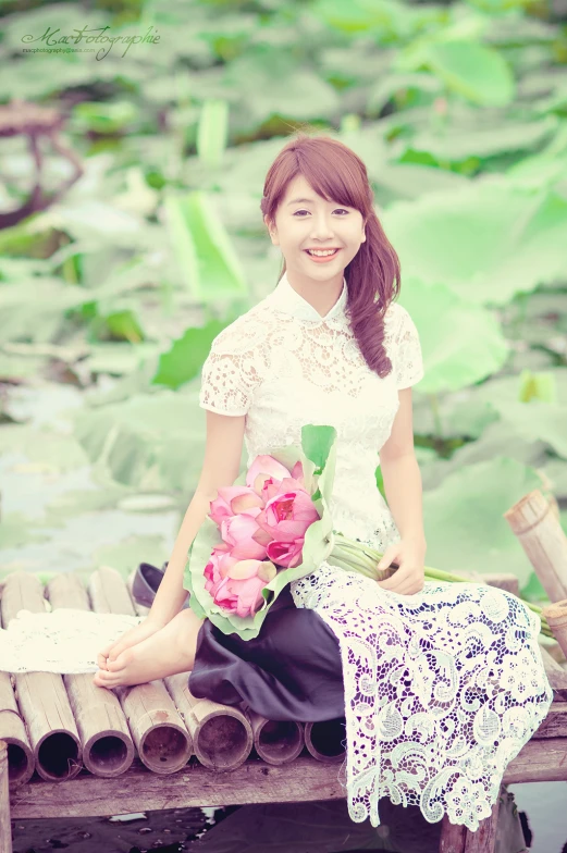 a woman sitting on top of a wooden plank holding a flower