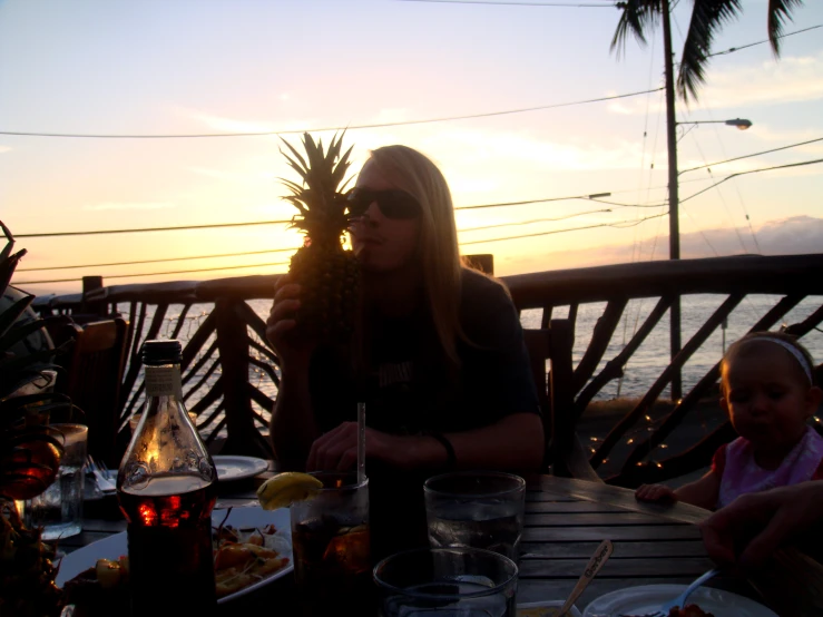 a woman and a child sitting at a table near the ocean