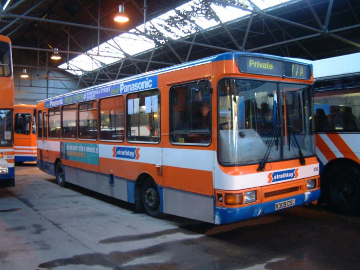 three buses parked inside a building waiting for passengers