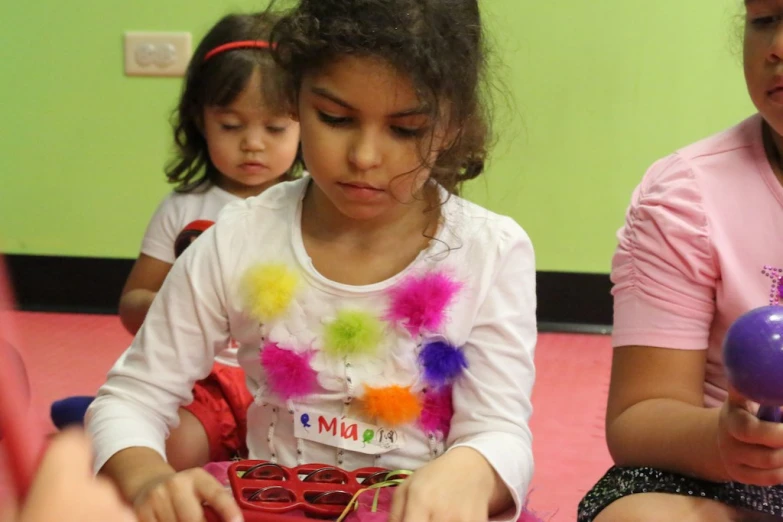 children using beads to learn craft ss while sitting on the floor