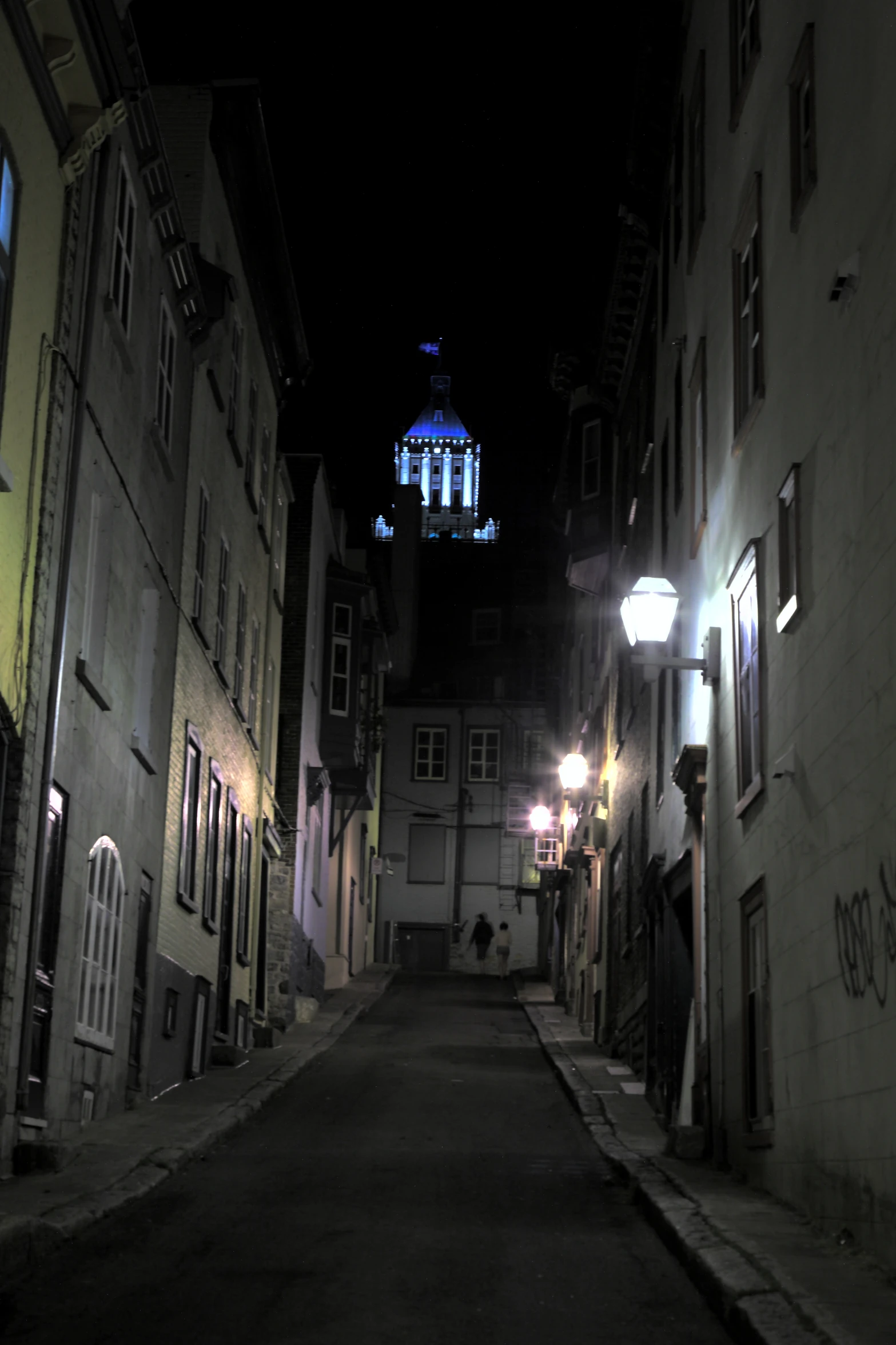 street lights illuminating on narrow residential area with church in background