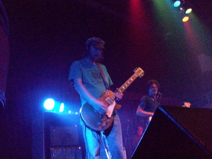 two men standing on stage playing musical instruments