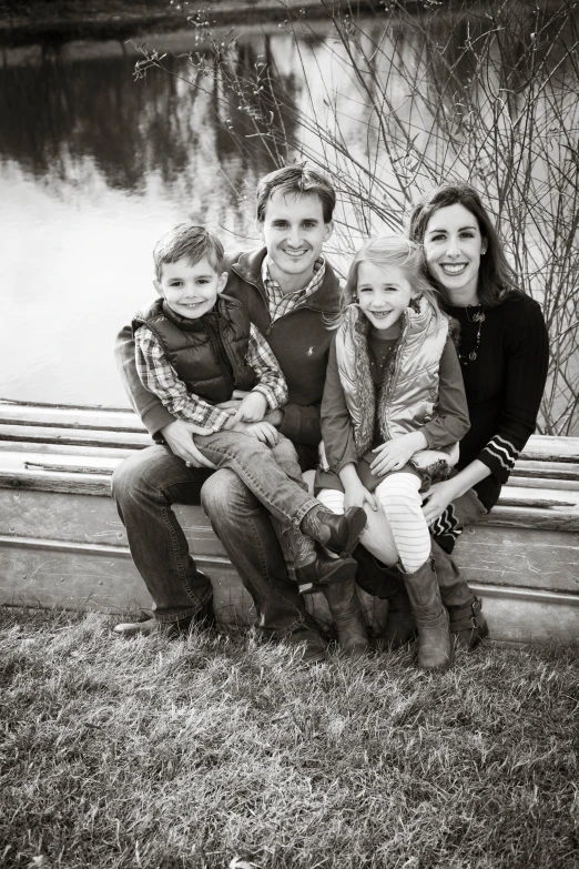 a family sits together on a bench beside the water