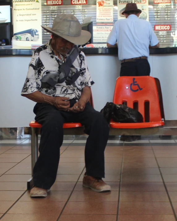 a man sitting down on a bench reading a book