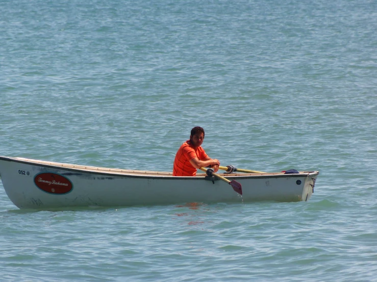 a man sits in a white boat on the ocean