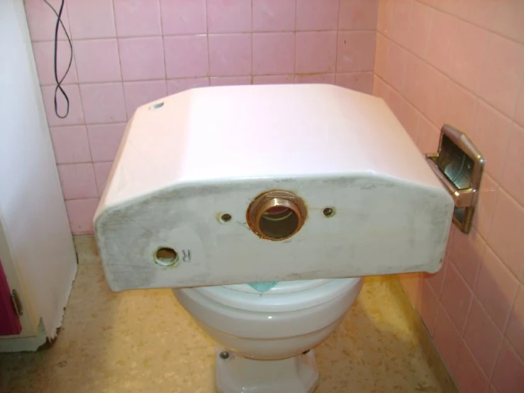 an old toilet in a pink tiled bathroom