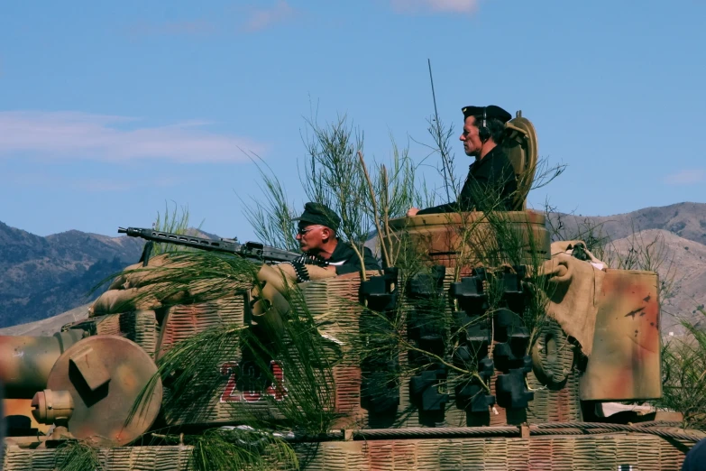 two men riding on the back of a military vehicle